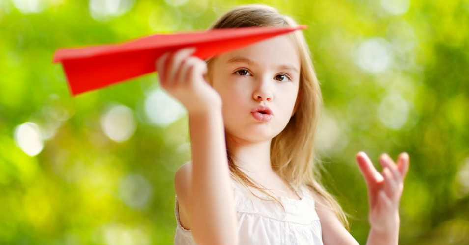 Adorable little girl holding a paper plane